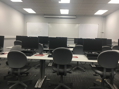 Rows of desks and computers facing a white board.